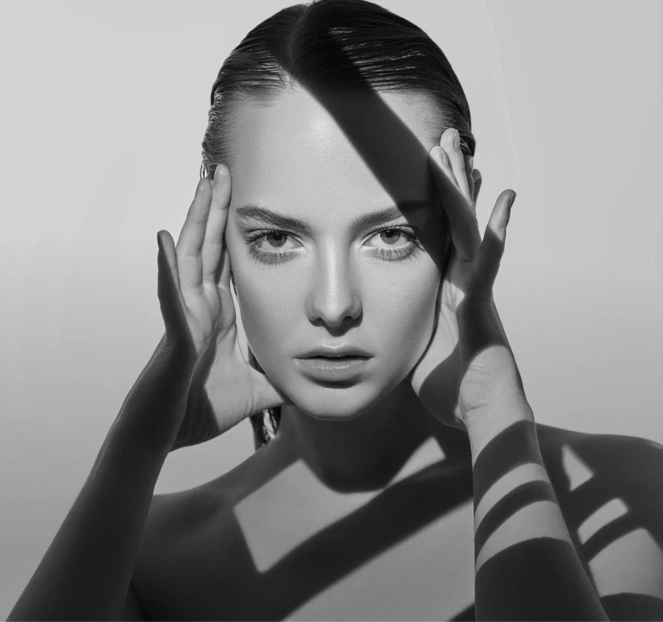 dramatic black and white image of woman with intense stare and sharp rectangular shadows casting over her face